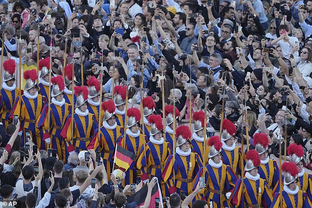 Swis guards march as white smoke billows from the chimney of the Sistine Chapel where 133 cardinals are gathering on the second day of the conclave
