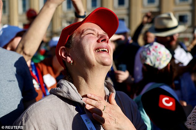 People react as white smoke rises from the chimney on the Sistine Chapel