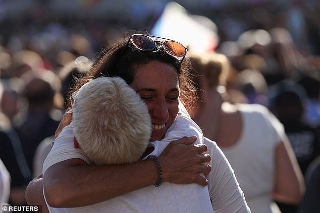 People waiting in the crowd hug after seeing the white smoke