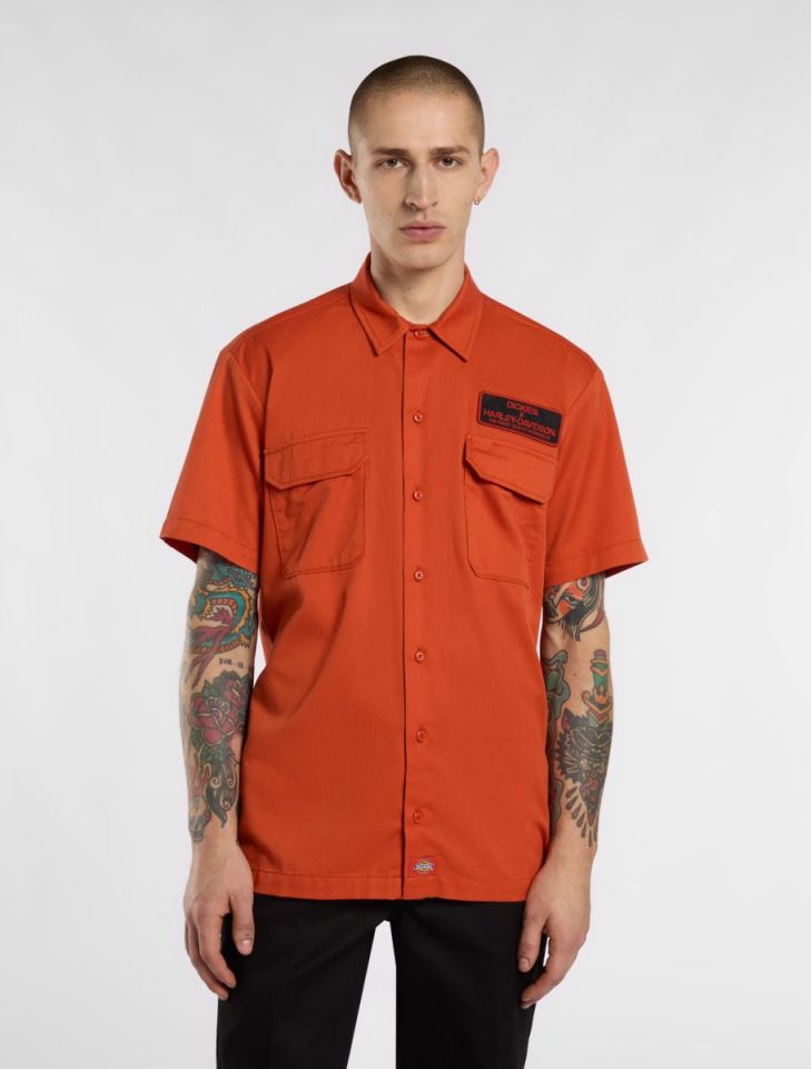 Man wearing an orange short-sleeved work shirt with a Harley-Davidson patch.