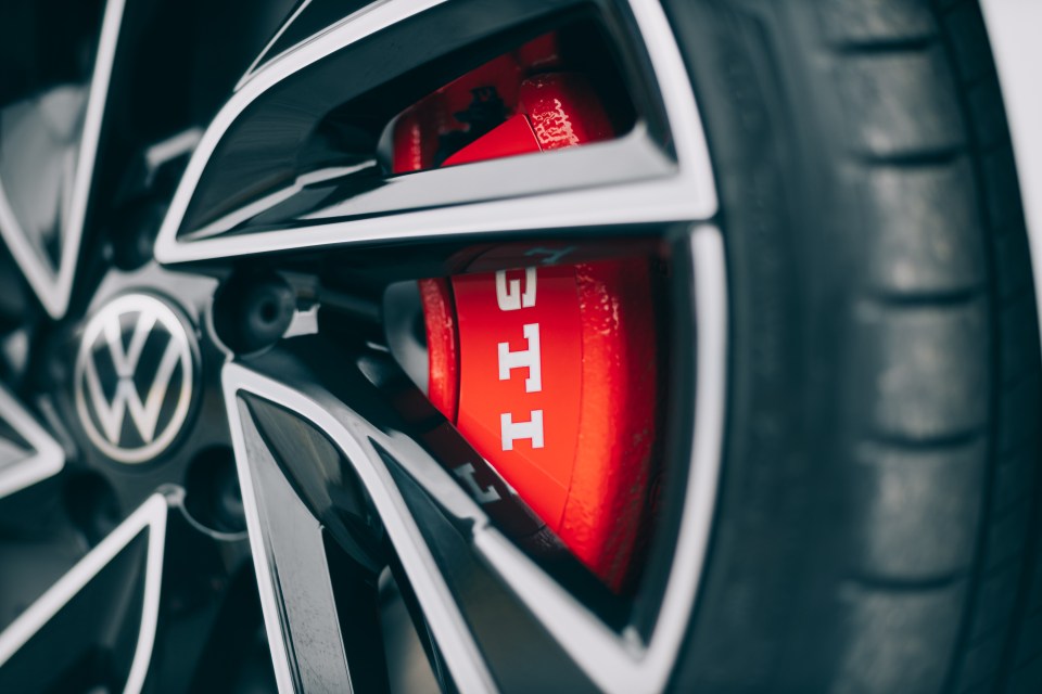 Close-up of a red GTI brake caliper behind a black wheel.