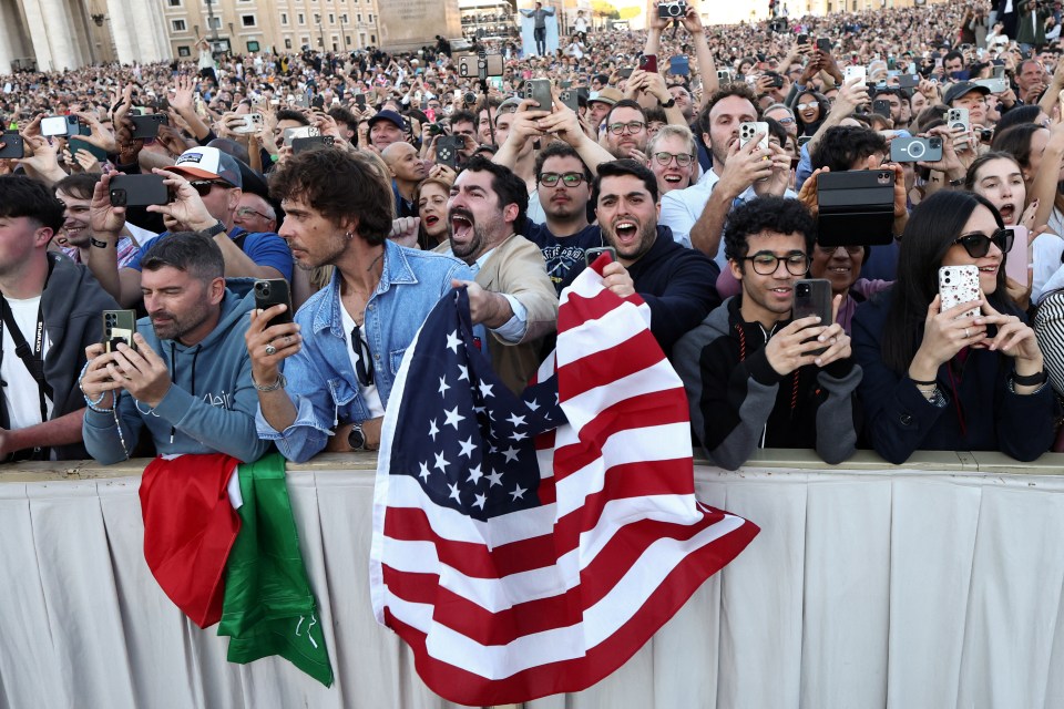 Crowd of people using phones to photograph the announcement of a new pope.