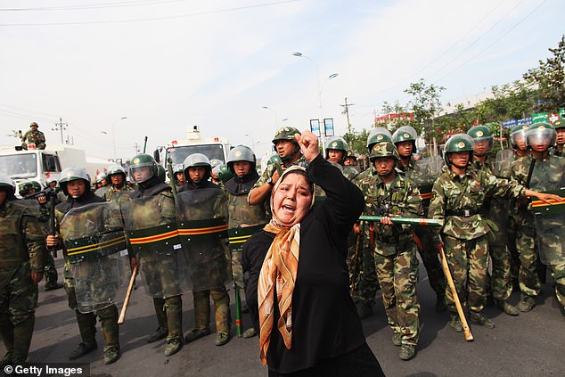 A Uyghur woman protests in front of policemen at a street on July 7, 2009 in Urumqi, the capital of the XUAR