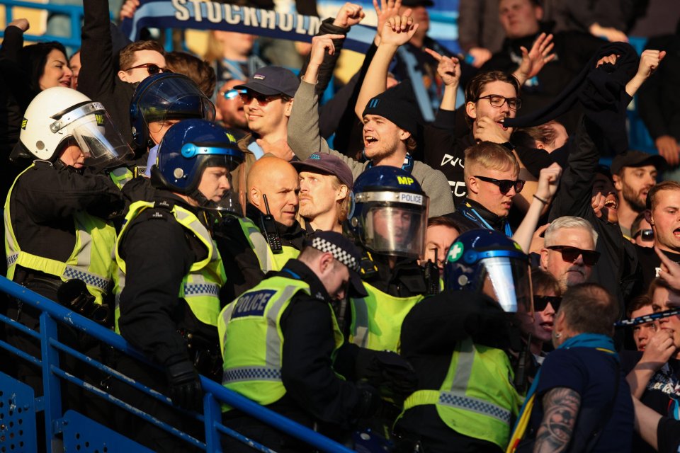Police officers monitoring Djurgarden fans at a soccer match.