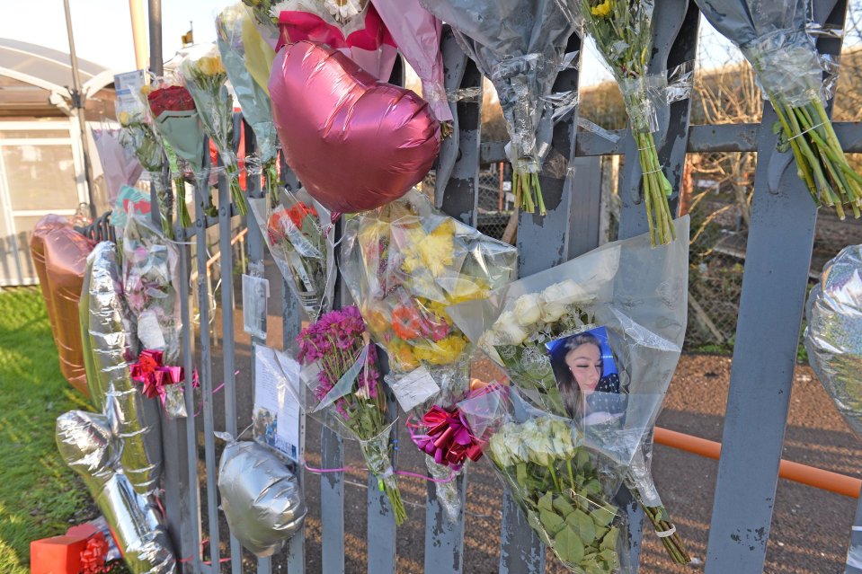 Flowers and balloons left at a fence as a memorial.