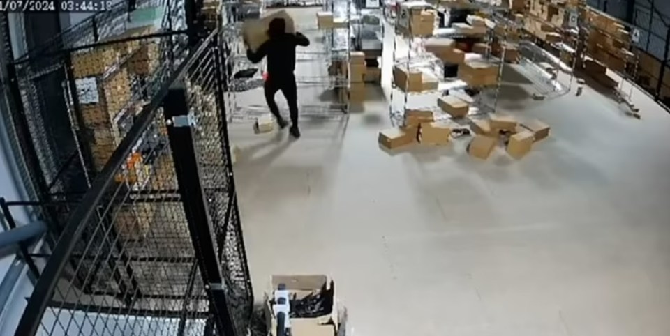 Security footage of a person stealing boxes from a warehouse.
