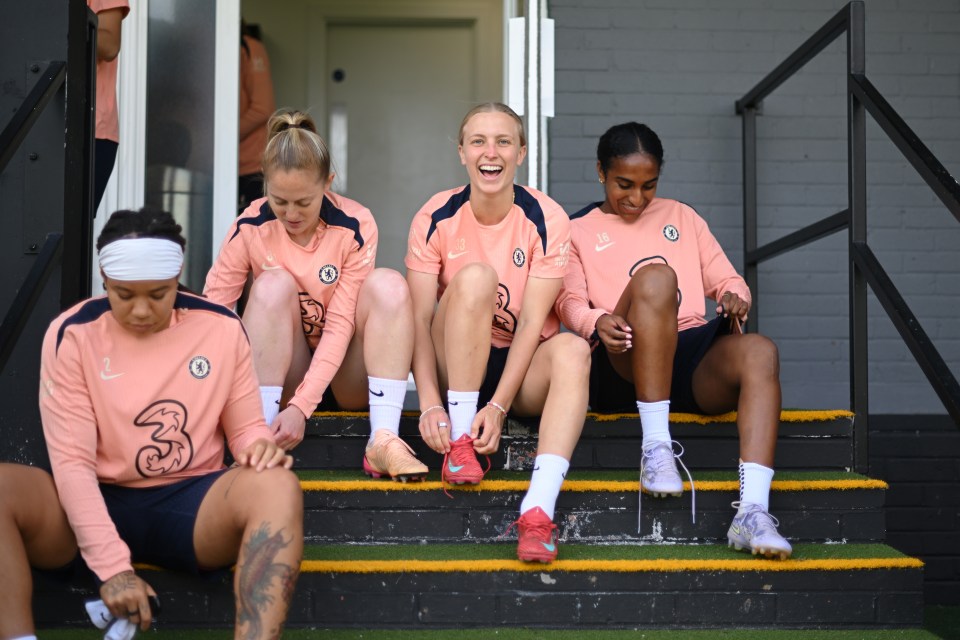Chelsea FC Women's team players sitting on steps, tying their cleats.