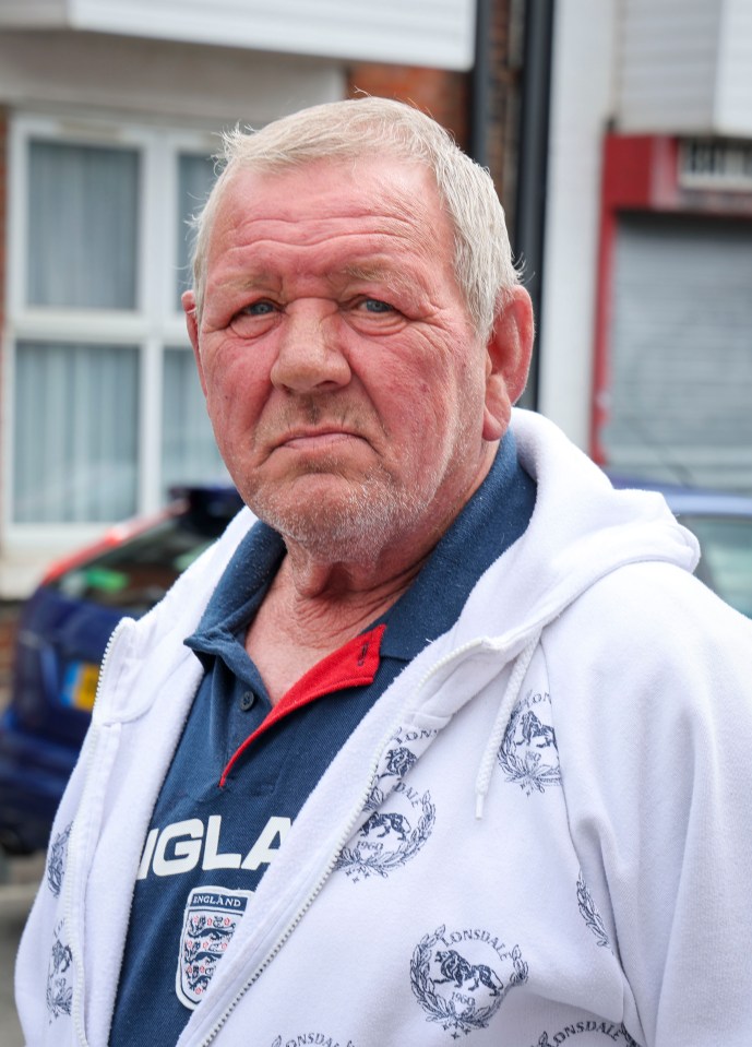 A man wearing a white Lonsdale zip-up hoodie over a navy England polo shirt.