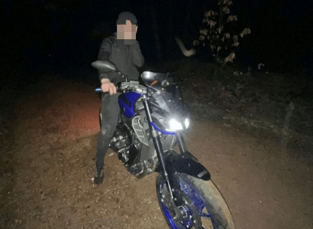 Person sitting on a blue motorcycle at night.