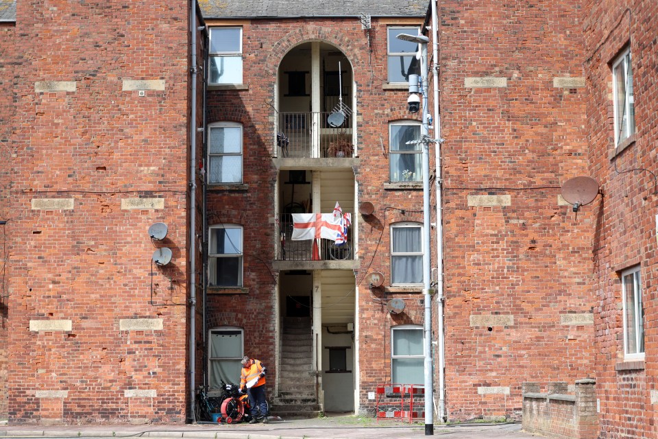 A worker stands outside a brick apartment building on Barrow Island, Cumbria.