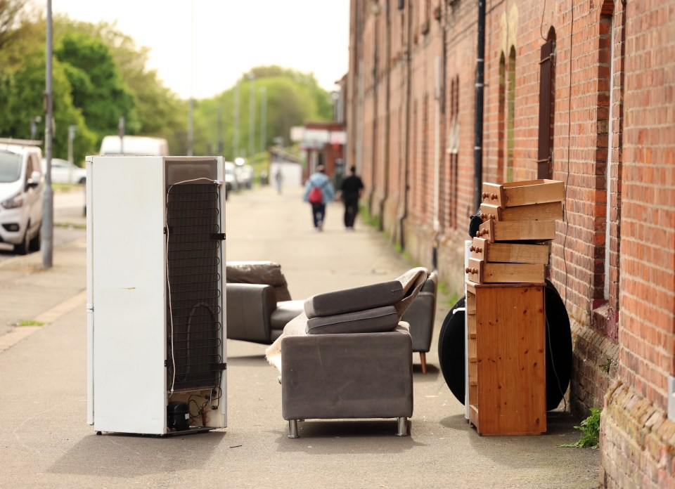 Discarded refrigerator, sofa, and dresser on a street.