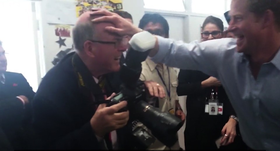 Prince Harry playfully placing his hand on a photographer's head.