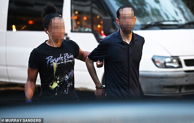 Another suspect is taken away by an officer after being arrested for bag snatching