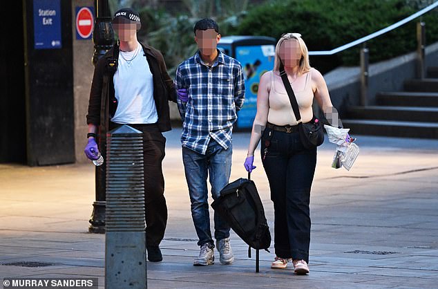 Plain clothes City of London police officers lead a suspect away