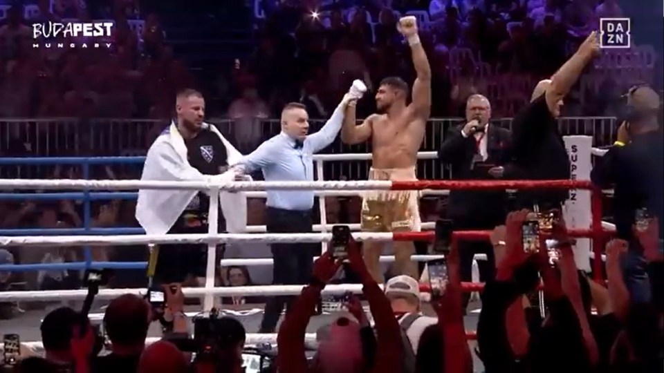 Boxer raises his hands in victory in a boxing ring.