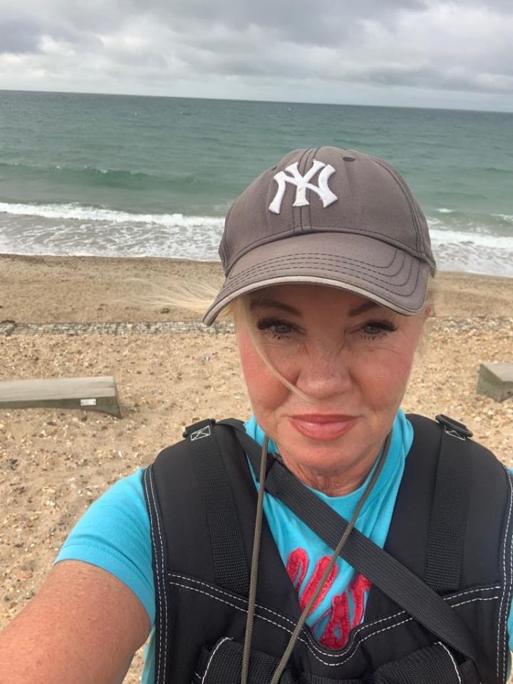 Woman wearing a baseball cap and vest at the beach.