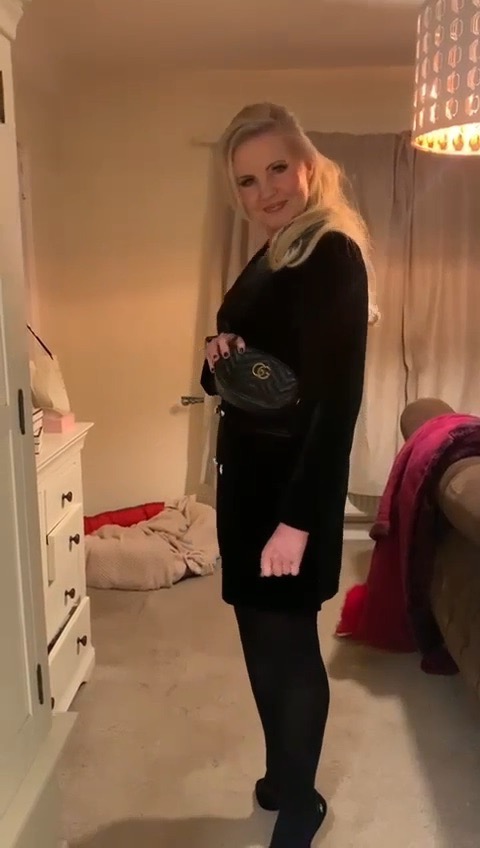 Woman in black dress and tights, holding a Gucci bag.