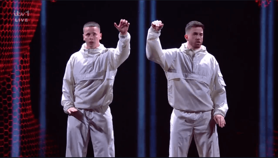 Two dancers in white outfits performing on stage.