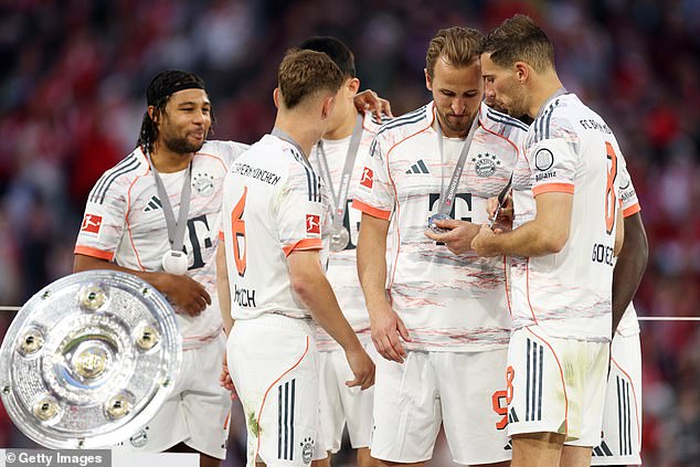 He took a moment to look at his winners medal as he spoke to some of his team-mates, including Leon Goretzka (right)