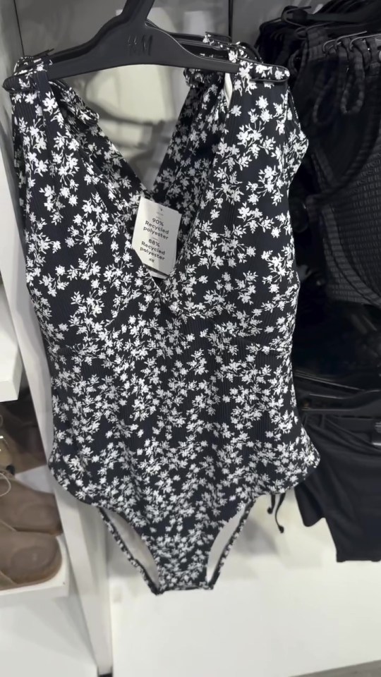 Black and white floral swimsuit on a hanger.