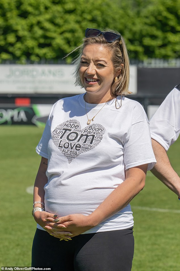 She sweetly cradled her growing baby bump and flashed a huge smile as she posed for the cameras at the charity event