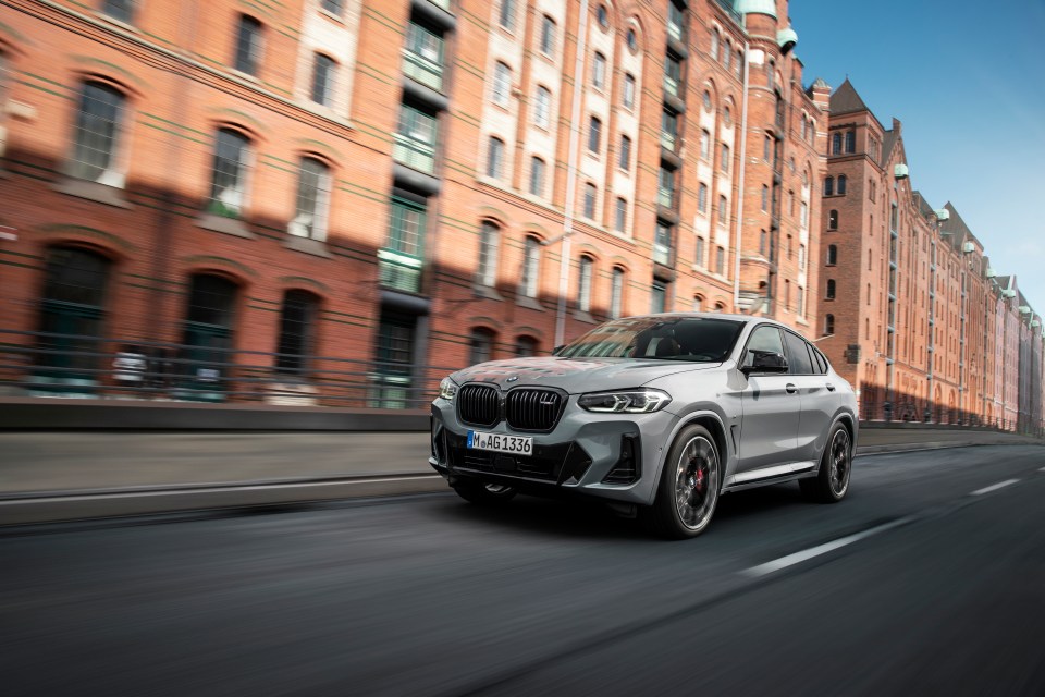 Silver BMW X4 driving on city street.