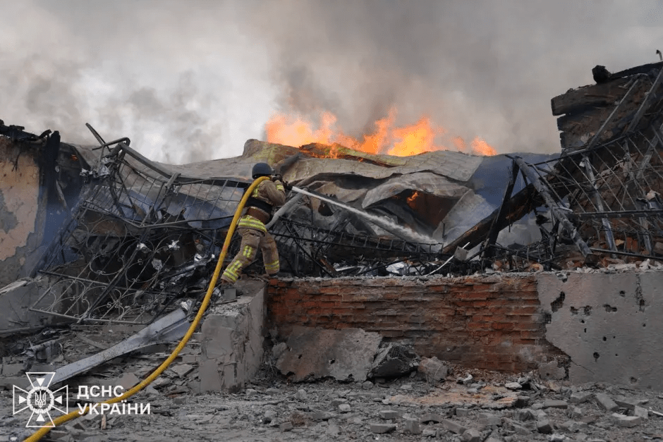 Firefighter battling a large fire at a destroyed building.