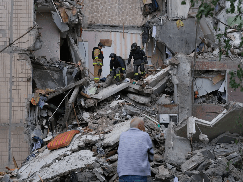 Firefighters searching through rubble at a collapsed building.