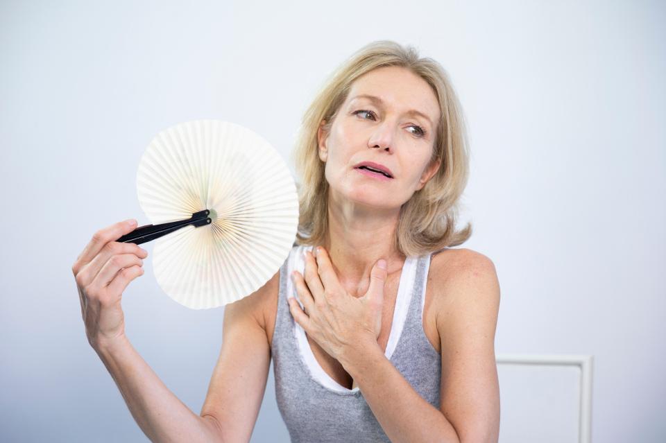 Menopausal woman experiencing a hot flash, fanning herself.