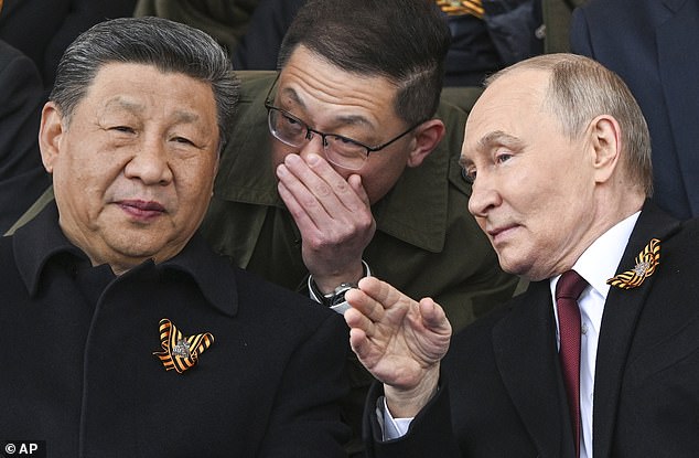 Russian President Vladimir Putin, right, and Chinese President Xi Jinping, left, talk as they watch the Victory Day military parade in Moscow, Russia, Friday, May 9, 2025, during celebrations of the 80th anniversary of the Soviet Union's victory over Nazi Germany during the World War II