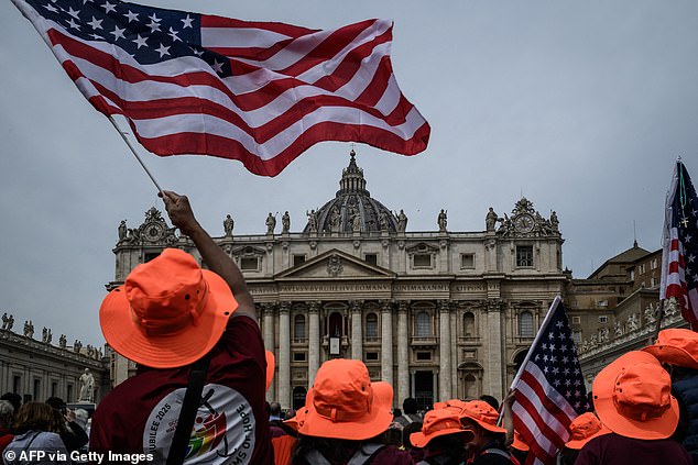 People gather with US flags at St Peter's square with the St Peter's Basilica in the background on the day Pope Leo XIV leads the Regina Caeli prayer, in the Vatican, on May 11, 2025