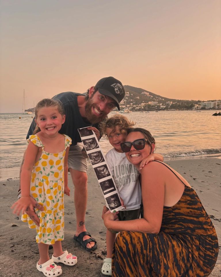 Family on beach holding ultrasound photo.