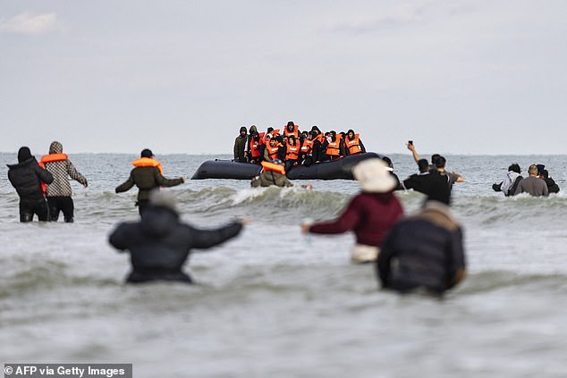 Migrants wave to a smuggler's boat in an attempt to cross the English Channel, on the beach of Gravelines, near Dunkirk, northern France on April 26, 2024