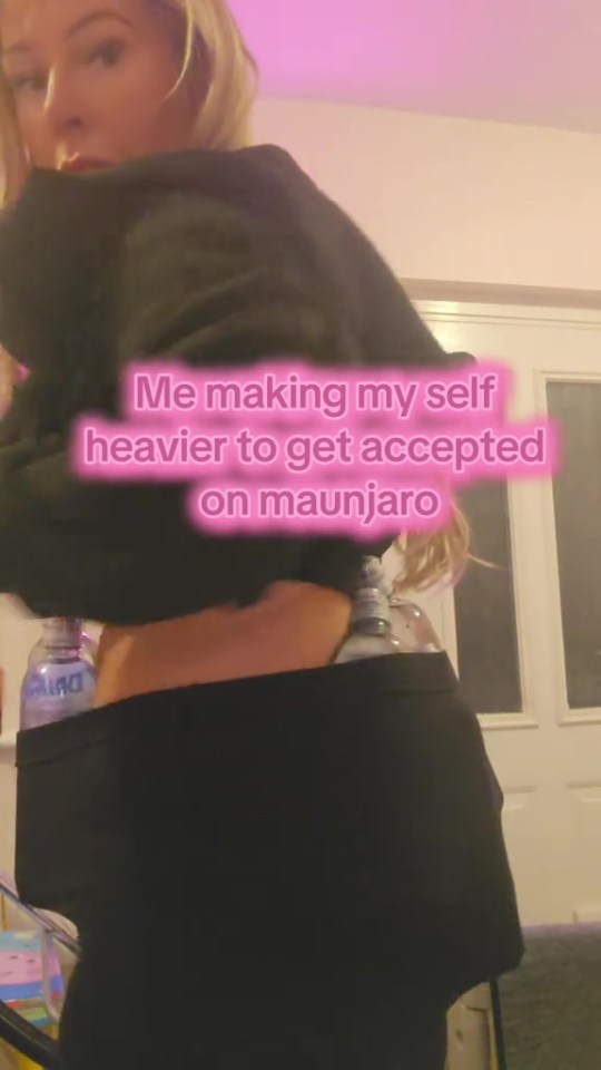 Person wearing a black top and leggings with water bottles tucked into their waistband, text overlay reads "Me making myself heavier to get accepted on Maunjaro".