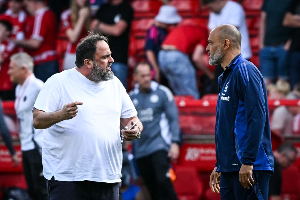 Two soccer coaches talking on the field.
