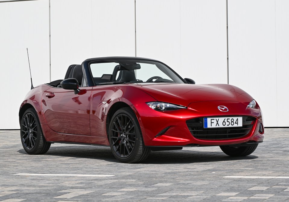 Red Mazda MX-5 convertible parked in a lot.