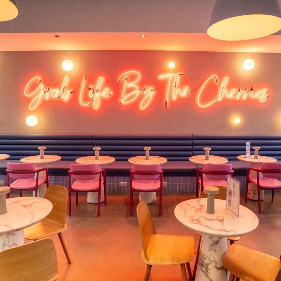 Interior of a cafe with a neon sign that says "Grab Life By The Cherries".