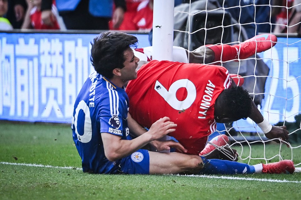Two soccer players colliding near the goal.