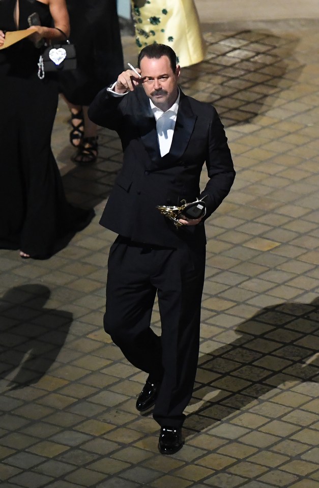 Danny Dyer leaving the BAFTA TV Awards 2025, holding an award and smoking a cigarette.