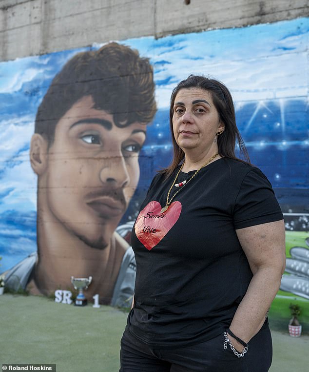Filomena De Mare, Santo's mother, stand in front of a A mural of Santo Romano, is behind.