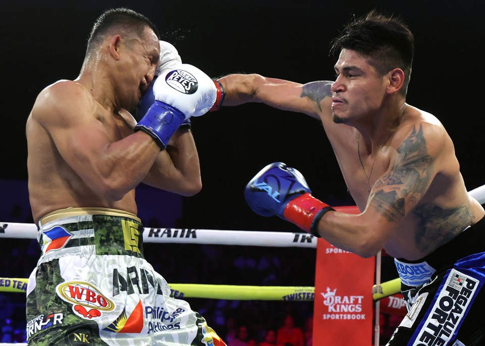 Boxers Emanuel Navarrete and Charly Suarez exchanging blows in a boxing match.