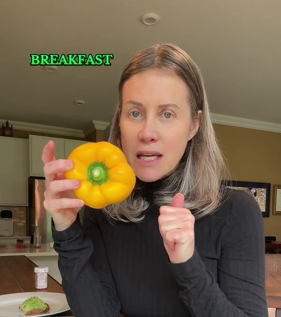 Woman holding a yellow bell pepper, saying it's a good source of vitamin C for breakfast.