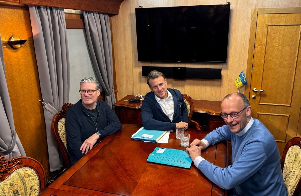 Keir Starmer, Emmanuel Macron, and Friedrich Merz in a meeting aboard a train.