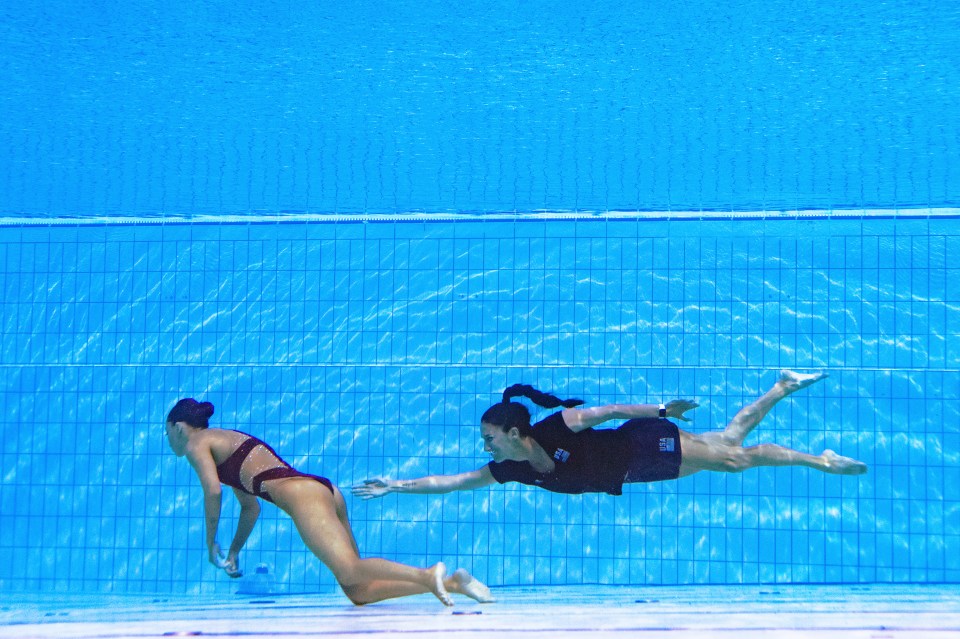 Underwater photo of a synchronized swimmer being rescued by her coach.