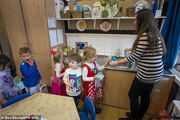 School children are helped to rinse their toothbrushes by a teacher inside a classroom at Fair Furlong Primary School in Bristol in March amid a national supervised toothbrushing campaign