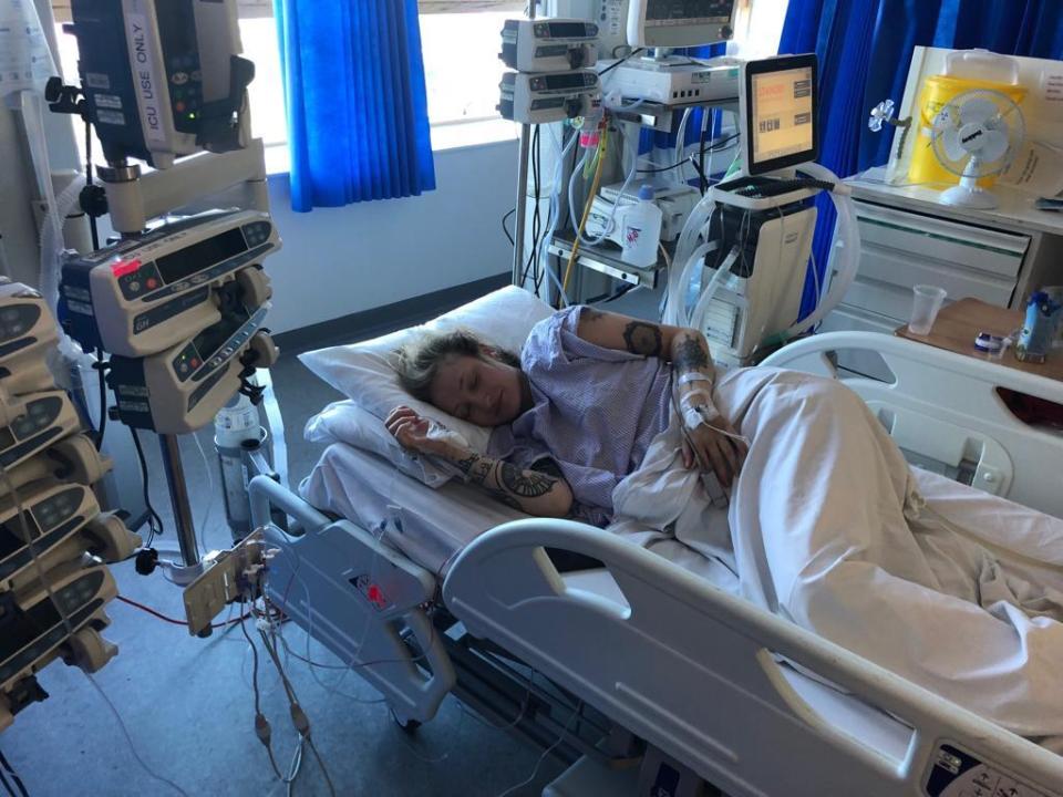 Woman sleeping in a hospital bed with medical equipment nearby.