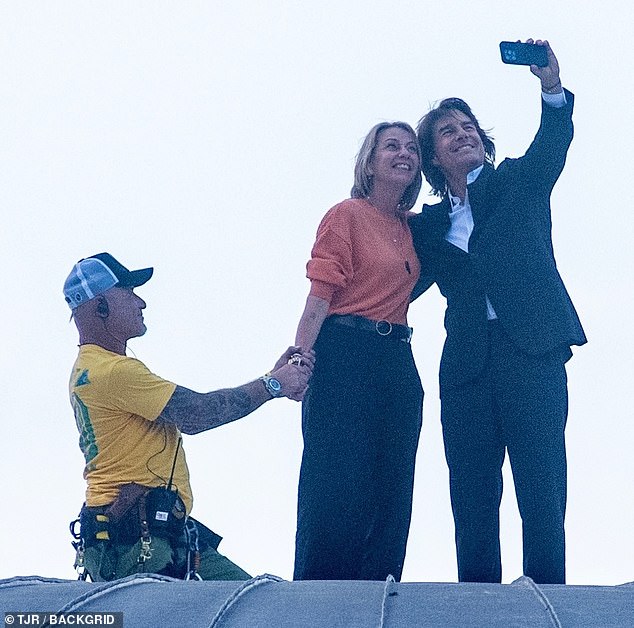 The rooftop event include a special moment for at least one special fan, as the actor was spotted snapping a woman in a bright-orange top. A stunt professional held her hand, though Cruise didn't appear to be secured to the roof in any way