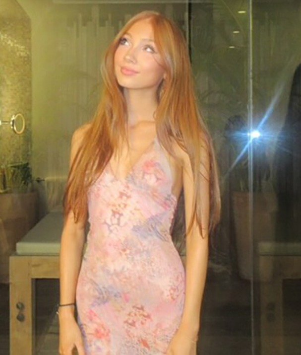 Woman in pink dress in front of a glass wall.