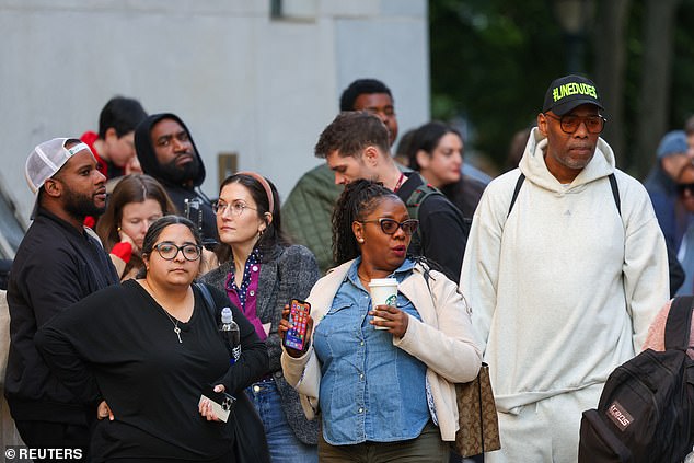 Members of the public wait outside the Manhattan courtroom as the trial got underway yesterday