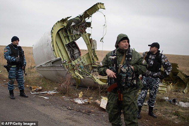 In this file photo taken on November 11, 2014 pro-Russian gunmen stand guard as Dutch investigators (unseen) arrive near parts of the Malaysia Airlines Flight MH17 at the crash site near the Grabove village in eastern Ukraine on November 11, 2014